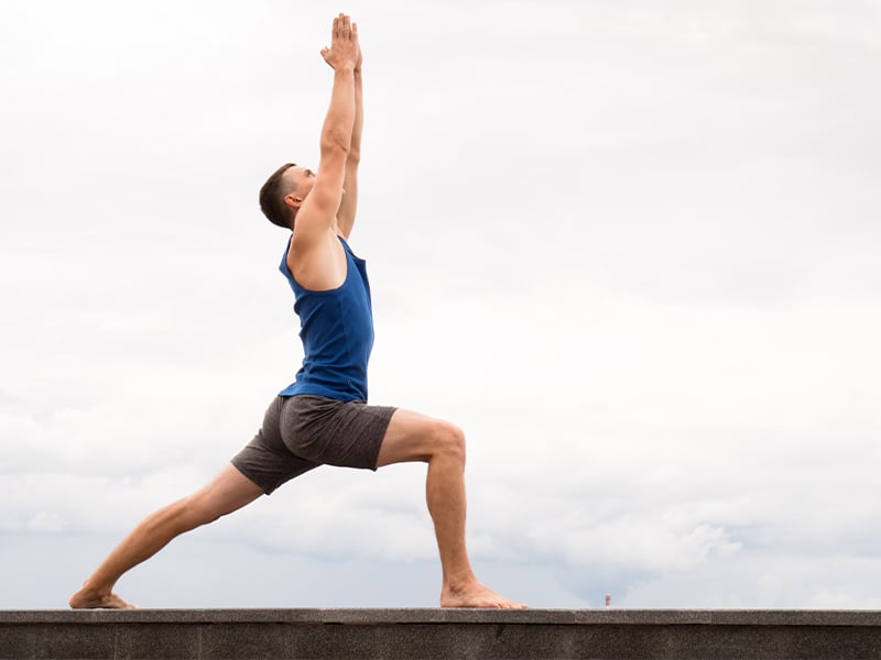 Ein Mann beim Yoga macht den Krieger 1.