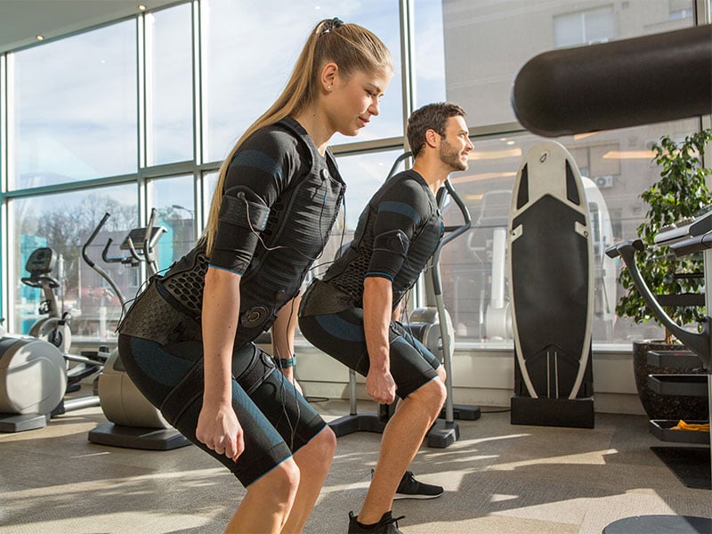 Beim EMS-Training ziehst du einen Anzug an, der deinem Körper Strom-Impulse versetzt. Dadurch ziehen sich deine Muskeln zusammen, ähnlich wie bei einer Kraftübung.