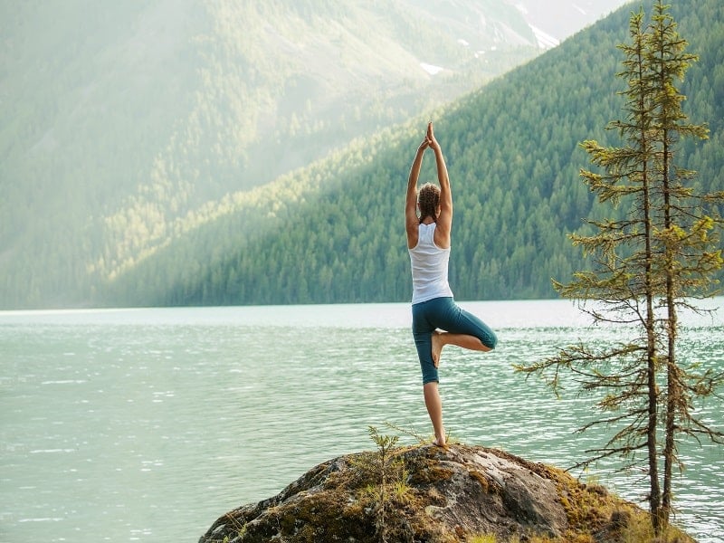 Die Outdoor-Yoga-Übung "Der Baum" kräftigt Hüfte und Knöchel & fördert Gleichgewicht sowie Konzentration.