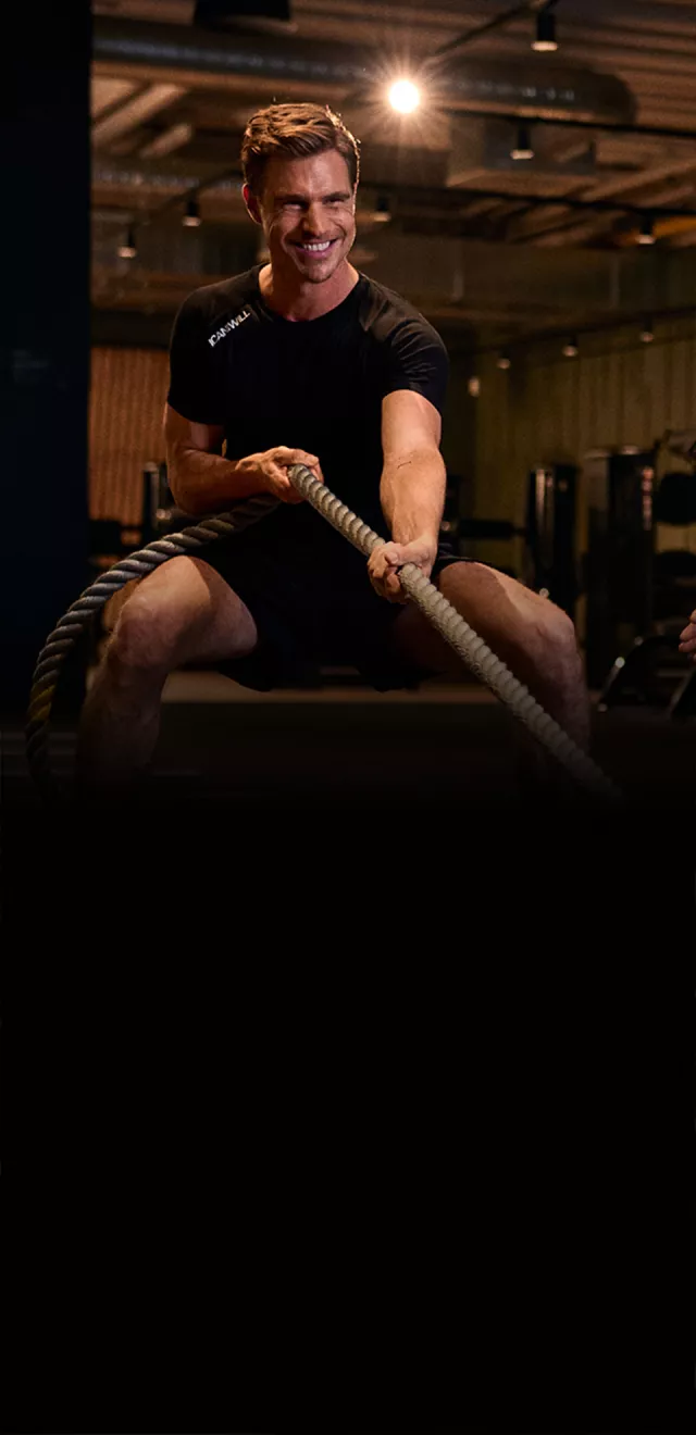 Junger Mann feuert Freund beim Sled Pull an.